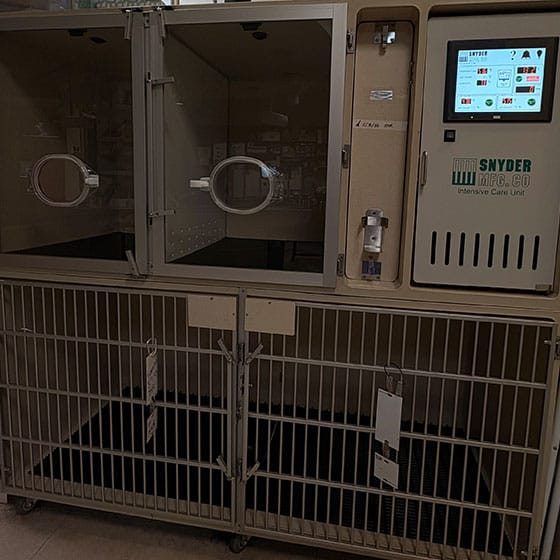A veterinary intensive care unit with two glass-fronted chambers on top, digital controls, and metal barred enclosures below; labeled "SNYDER MFG. CO." on the right with a touchscreen panel.